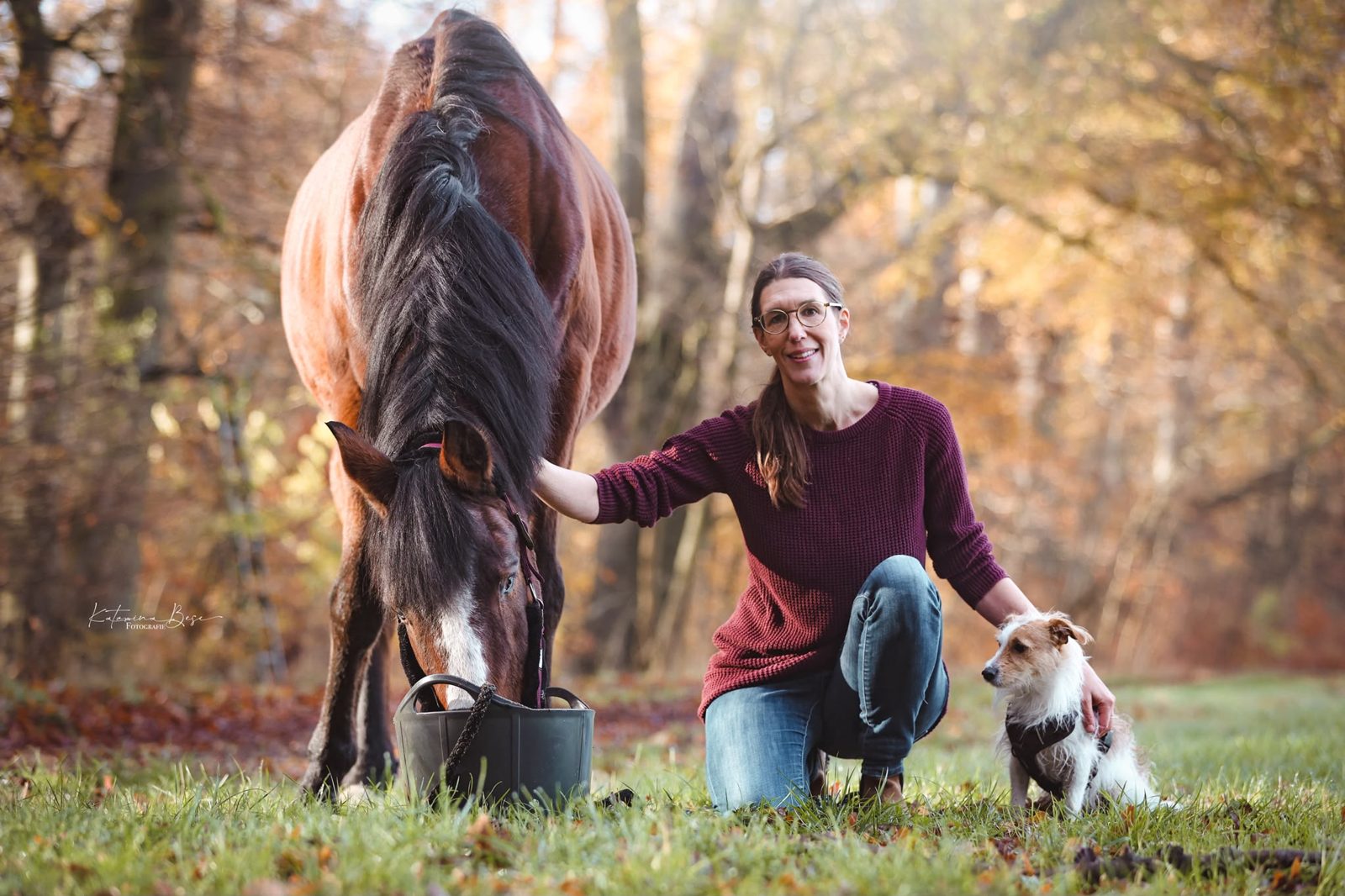 Corinna Preuße mit ihrem Pferd und ihrem Hund im Herbstwald